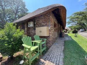 two green chairs sitting outside of a brick building at Hazyview Kruger Lodge in Hazyview