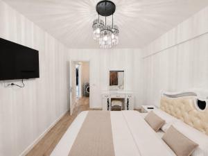 a white living room with a couch and a tv at Abel 27 Residence in Bacău