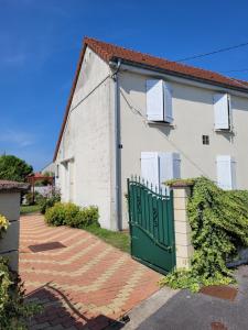 a white house with a green gate in front of it at Gîte Les Galipes in Mareuil-sur-Ay