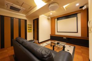 a living room with a couch and a projection screen at ホテルリノ in Kitakyushu