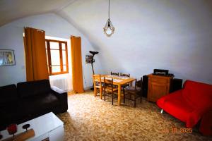 a living room with a table and a red couch at Gîte des pêcheurs, Gorges du Tarn in Mostuéjouls +13 photos