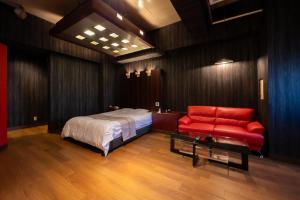 a bedroom with a bed and a red couch at ホテルリノ in Kitakyushu +13 photos