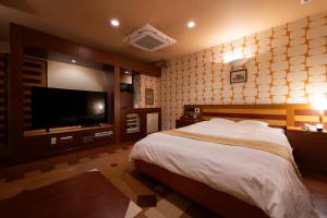 a bedroom with a bed and a flat screen tv at ホテルリノ in Kitakyushu