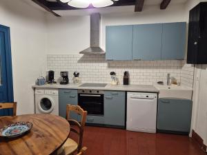a kitchen with blue cabinets and a table and a stove at Le port des Chalands meublé de tourisme 3 étoiles in Saint-Georges-sur-Cher