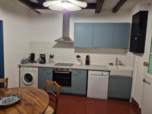 a kitchen with blue cabinets and a table and a sink at Le port des Chalands meublé de tourisme 3 étoiles in Saint-Georges-sur-Cher +20 photos