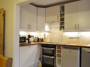 a kitchen with white cabinets and a stove top oven at Beny Cot in Keswick