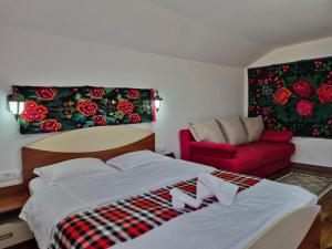 a bedroom with a bed and a red couch at Casa Papițu in Vadu Izei