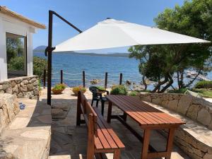 a picnic table with an umbrella and a view of the water at Over The Sea Punta Lada in Porto Rotondo