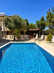 a blue swimming pool with trees and a house at Unique Beach Luxurious Villas in Ayia Napa