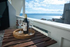 a bottle of wine and two wine glasses on a balcony at Apartmani Liovic in Duće