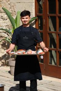 a man in an apron holding a tray of food at Hotel Restaurant Mas Roig - Adults only in Pals +110 photos
