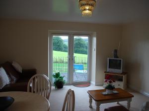 a living room with a couch and a tv and a table at Shallcross Hall Cottage - Toddbrook - Whaley Bridge in Taxal