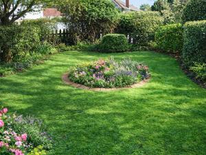 a garden with a circle of flowers in the grass at Starboard Cottage in Winterton-on-Sea