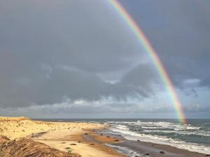 a rainbow over a beach with the ocean at Starboard Cottage in Winterton-on-Sea