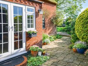 a brick house with a window and potted plants at Starboard Cottage in Winterton-on-Sea