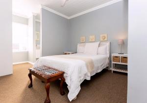 a white bedroom with a bed and a table at Helios House in Langebaan