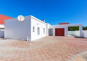 a white house with a red garage and a basketball hoop at Helios House in Langebaan