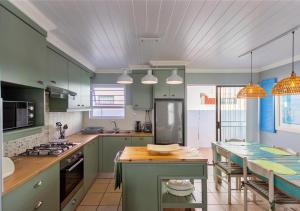 a kitchen with green cabinets and a table in it at Helios House in Langebaan