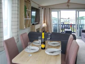 a dining room table with wine bottles and glasses at Premier Caravan 10 in Tywyn