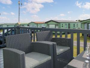 two wicker chairs and a table on a balcony at Premier Caravan 10 in Tywyn +5 photos