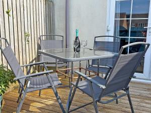 a glass table with two chairs and a bottle of wine at Twenty One in Westward Ho