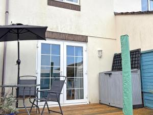 a patio with a table and chairs and an umbrella at Twenty One in Westward Ho