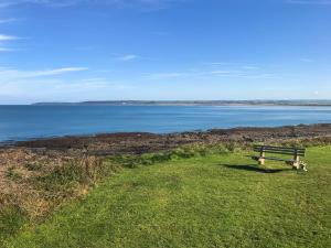 a bench sitting on the grass near the water at Twenty One in Westward Ho
