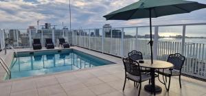a balcony with a table with an umbrella and a pool at Edifício Kings Tower T2-06 in Luanda