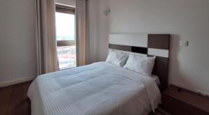 a bedroom with a large white bed with a window at Edifício Kings Tower T2-06 in Luanda