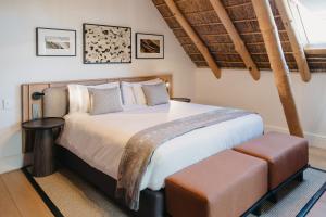 a bedroom with a large white bed and a stool at Rickety Bridge Estate in Franschhoek