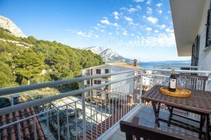 a balcony with a table with a bottle of wine at Apartmani Liovic in Duće