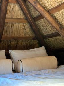 a bed in a thatched room with two pillows at Cabin by the pond in Wądołki Bućki