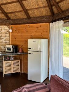 a white refrigerator in a kitchen with a wooden ceiling at Cabin by the pond in Wądołki Bućki +21 photos
