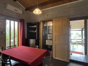 a dining room with a red table and a kitchen at Holiday Home Le Terrazze del Geco Bungalow A - SLR300 by Interhome in San Lorenzo al Mare