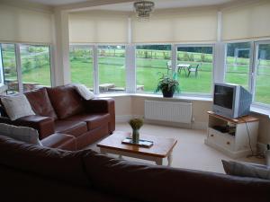 a living room with a couch and a tv at Shallcross Hall Cottages - Combs in Taxal