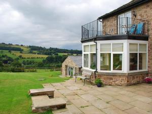 a brick house with a balcony and a bench at Shallcross Hall Cottages - Combs in Taxal +2 photos