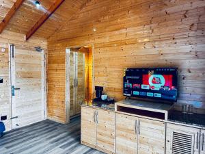 a living room with a tv in a wooden cabin at The Walnut Homes- Luxury Pine Cottages in Bhīm Tāl