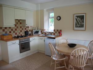 a kitchen with a table and a table and chairs at Shallcross Hall Cottages - Blackbrook in Taxal