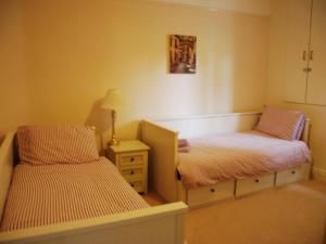 a room with two beds and a night stand with a lamp at Shallcross Hall Cottages - Blackbrook in Taxal +4 photos