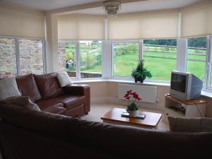 a living room with a couch and a tv at Shallcross Hall Cottages - Blackbrook in Taxal