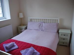 a bedroom with a red and white bed with purple pillows at Shallcross Hall Cottages - Blackbrook in Taxal