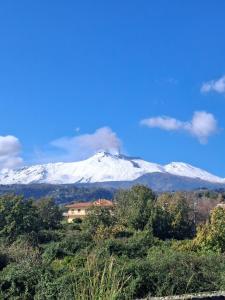 a snow covered mountain in the distance with a house at La casa di Nerone in Acireale