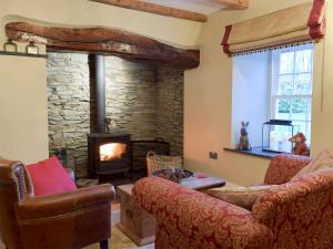 a living room with a stone fireplace and couches at Fountain Hill in Eglwyswrw