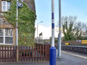 a fence next to a building with a ivy covered wall at Station Cottage in Silverdale