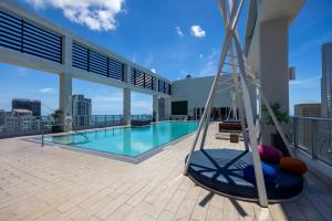 a swing on the balcony of a building with a pool at Stylish Pool Stay Near Brickell & Beach in Miami