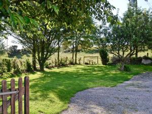 a wooden fence in a field with trees and grass at Horsepark Cottage in Girthon