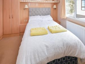 a large white bed with two yellow pillows on it at Stanley's Sanctuary in Boot