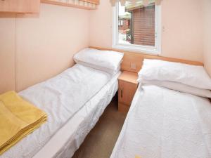 two beds in a small room with a window at Stanley's Sanctuary in Boot
