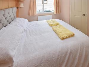 a white bed with two yellow towels on it at Stanley's Sanctuary in Boot