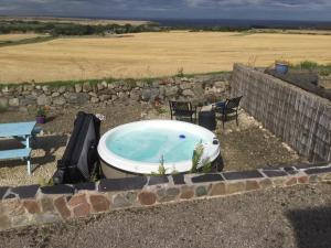 a bath tub sitting in a yard with two chairs at The Brae Steading in Fordyce +3 photos